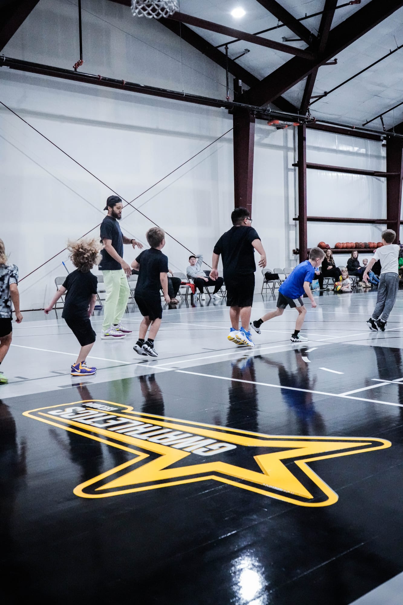 Young athletes in a session on the Game Winner court while families watch